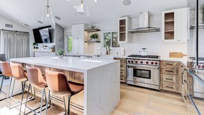 A modern kitchen with a central island, stainless steel appliances, and wooden cabinetry. - South Bay Sweet Spot: Walk to Hermosa & MB Piers 5 bdrm home 2 Blocks from Beach (Hermosa Beach)