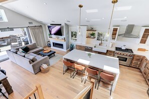 Un soggiorno moderno open space con cucina, zona pranzo e camino.