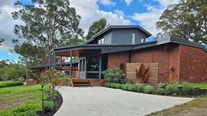 A modern house with a brick exterior, a concrete driveway, and a well-maintained garden. - Apple Tree Studio - country luxury self-contained studio (Kilmore)