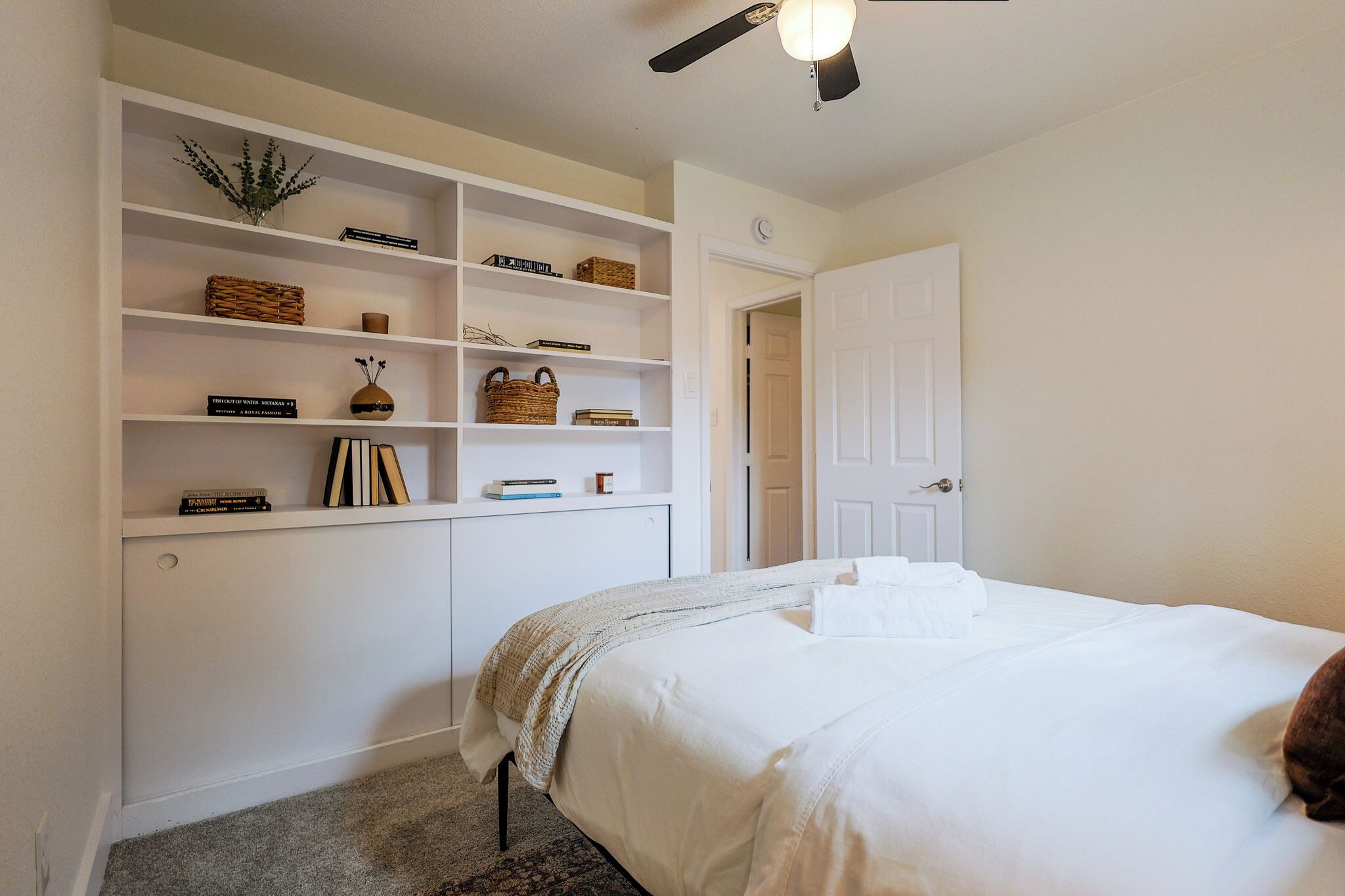 A bedroom with a bed, a white wardrobe, and a ceiling fan.