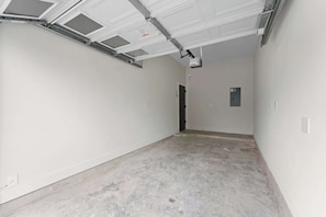 A clean, empty hallway with white walls, a concrete floor, and a garage door. - Maison Covington: Modern Luxury 3BR Retreat Near Houston Hotspots (Houston)