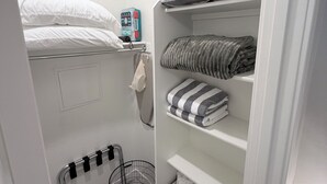 Et lille værelse med køjeseng, en hylde med foldede håndklæder, en kurv og et førstehjælpssæt.