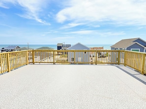 A beachside property with a fenced deck, a gravel patio, and houses in the background.