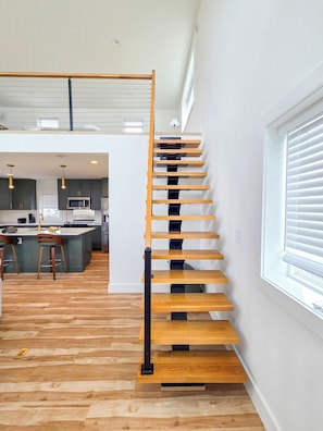 A modern interior with a wooden staircase, a kitchen area, and a dining space.