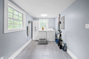 A laundry room with a washing machine, dryer, and stacked laundry baskets.