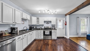 A kitchen with white cabinets, stainless steel appliances, and a wooden floor. - Cozy 2 Bedroom 1 Bath home in the heart of Clarksville (Clarksville)