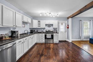 A kitchen with white cabinets, stainless steel appliances, and a wooden floor. - Cozy 2 Bedroom 1 Bath home in the heart of Clarksville (Clarksville)