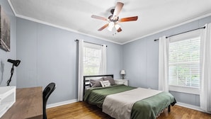 A bedroom with a bed, a desk, a chair, a ceiling fan, and windows with curtains. - Cozy 2 Bedroom 1 Bath home in the heart of Clarksville (Clarksville)