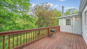 A wooden deck with a barbecue grill, a white door, and a chimney.