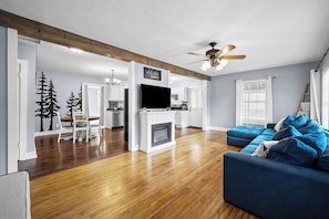 A modern living room with a fireplace, a blue sofa, and a television. - Cozy 2 Bedroom 1 Bath home in the heart of Clarksville (Clarksville)