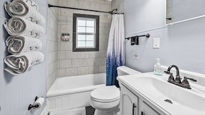 A bathroom with a bathtub, toilet, and sink. There are towels on the wall, a window, and a shower curtain. - Cozy 2 Bedroom 1 Bath home in the heart of Clarksville (Clarksville)