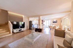 A modern living room with a flat-screen TV, a coffee table with a vase, a sofa, and a staircase leading to another room. - Villa Nerea, Private Villa Near Taormina (Taormina)