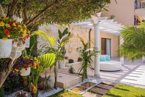 A garden with a white outdoor seating area, a stone wall, and various plants. - Villa Nerea, Private Villa Near Taormina (Taormina)