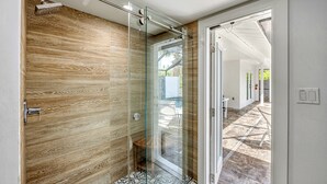 Ein modernes Badezimmer mit Duschkabine aus Glas, Holzvertäfelung und einem gemusterten Boden.