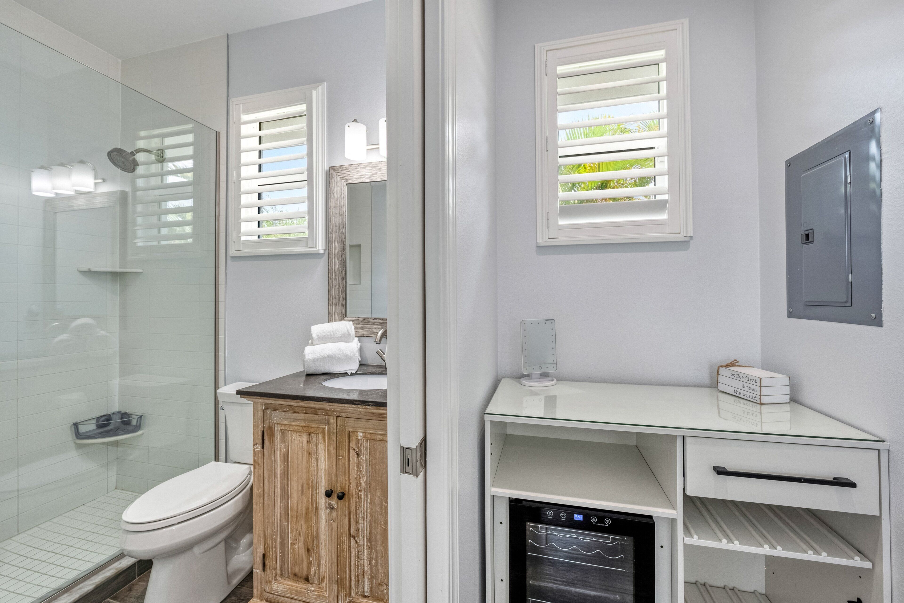 A bathroom with a glass shower enclosure, a white toilet, a wooden cabinet, a glass sink, and a built-in dishwasher.