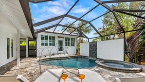 Ein Swimmingpool mit Liegestühlen und einer Whirlpool, umgeben von einem Haus mit weißer Fassade und einer überdachten Glasveranda.