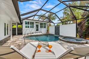A swimming pool with lounge chairs and a hot tub, surrounded by a house with a white exterior and a glass-enclosed patio. - Brisas Del Mar | Private Pool with Spa, Guest House, Near Siesta Key Beach (Siesta Key)