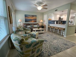 A living room with a sofa, two armchairs, a coffee table, and a painting on the wall. - EC122 Shared Pool, Pet Friendly, Boardwalk to the Beach (Port Aransas)