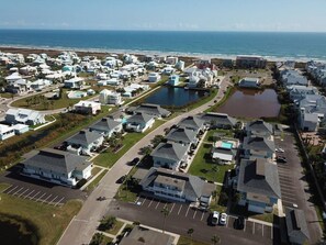 An aerial view of a coastal residential area with houses, a beach, and a large body of water. - EC122 Shared Pool, Pet Friendly, Boardwalk to the Beach (Port Aransas)