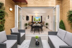 A patio with wicker furniture, a dining table set, and potted plants.
