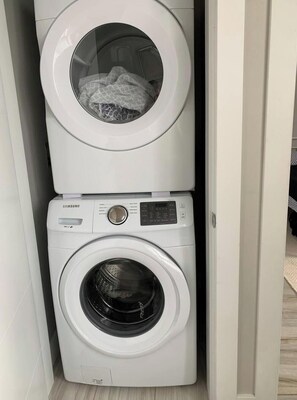 En tvättmaskin och torktumlare som är placerade ovanpå varandra, med en kontrollpanel och en synlig lucka.