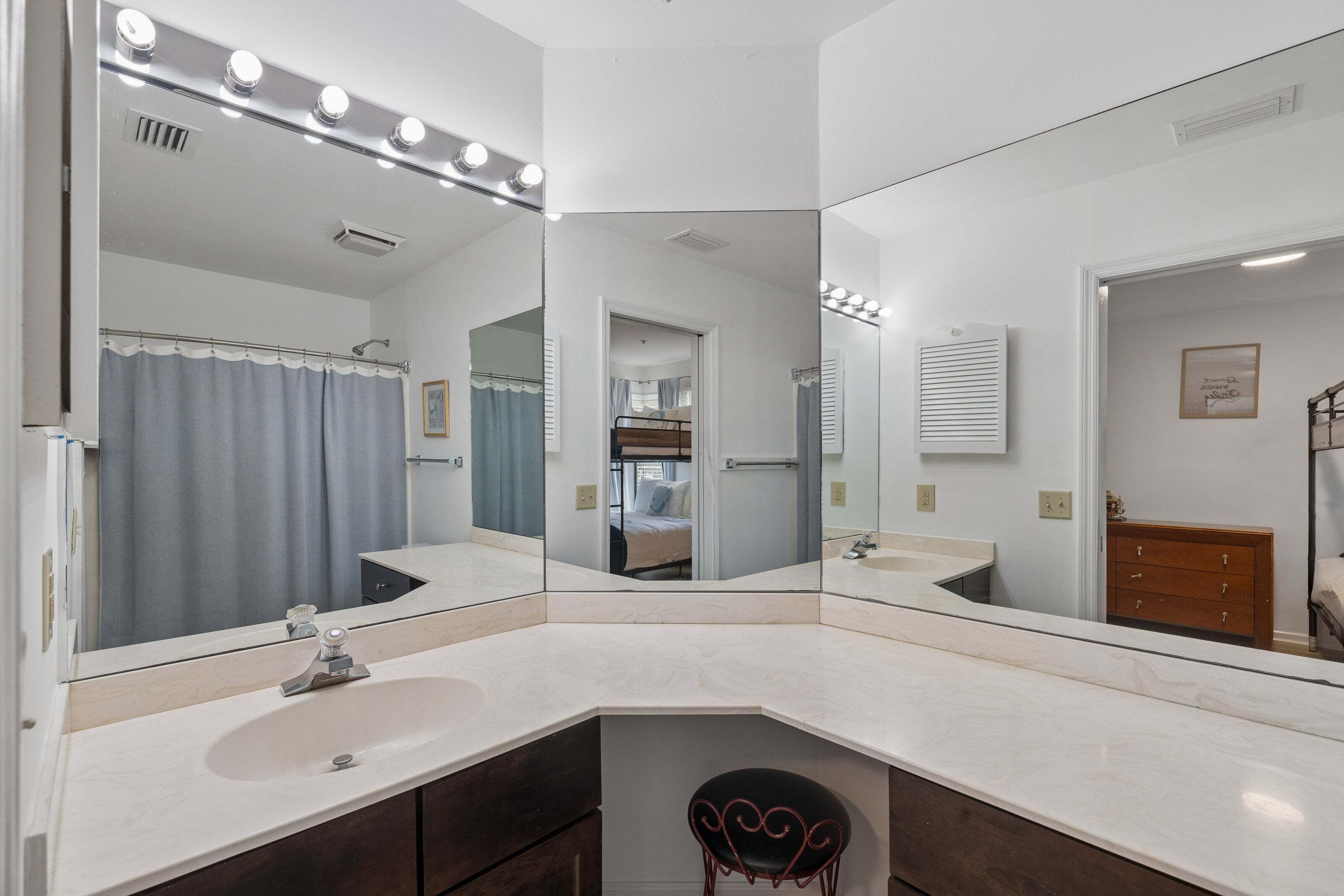 Une salle de bain avec un grand miroir, un meuble-lavabo et un rideau de douche.
