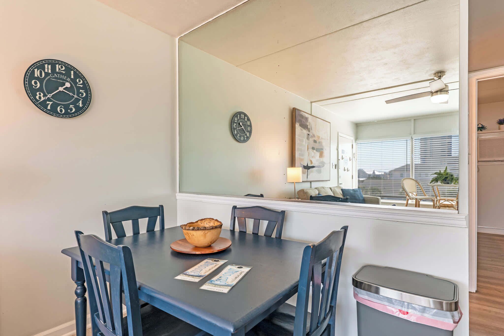 Un coin repas avec une table, des chaises, un bol et deux horloges au mur.