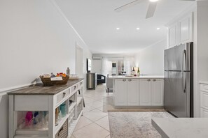 A modern kitchen with white cabinetry, a stainless steel refrigerator, and a central island. - Forest Beach Condo | Community Pool | Oceanfront Private Beach Access | Elegant Furnishings (Hilton Head Island)