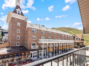 Ein mehrstöckiges Hotel mit einem markanten Turm, Balkonen und einem überdachten Außenbereich mit Sitzgelegenheiten.