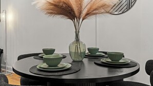 A round dining table with a vase of pampas grass, green bowls, and plates. -   Modern 3BR Home Patio Near Center City Free Parkin (Philadelphia)