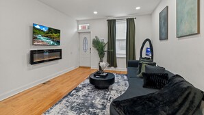 A modern living room with a flat-screen TV, a fireplace, a sofa, and a large window with curtains. -   Modern 3BR Home Patio Near Center City Free Parkin (Philadelphia)