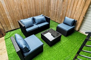 A patio area with a black wicker sofa set, two matching armchairs, a small black table, and a green artificial grass floor. -   Modern 3BR Home Patio Near Center City Free Parkin (Philadelphia)