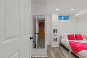 A bedroom with a bed, a red throw blanket, a wooden staircase, and a white door. -   Modern 3BR Home Patio Near Center City Free Parkin (Philadelphia)