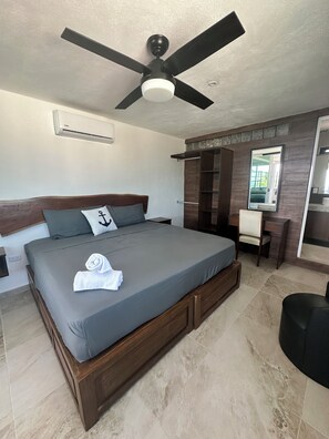 A bedroom with a bed, a ceiling fan, a mirror, and a small desk. - Incredible oceanfront home with private pool (Cancún)