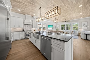 A modern kitchen with white cabinetry, a large island, stainless steel appliances, and pendant lighting. - Walk to Gulf Place~Private Pool~Dogs OK~EV Charger (Santa Rosa Beach)