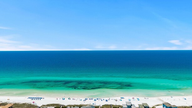 A beach with clear turquoise waters, white sand, and a row of beach umbrellas. - Heated Pool~1/2 mile to Beach~Dogs OK~Fenced Yard (Santa Rosa Beach)