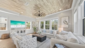 A spacious living room with a large TV, comfortable seating, and a ceiling fan. - Heated Pool~1/2 mile to Beach~Dogs OK~Fenced Yard (Santa Rosa Beach)
