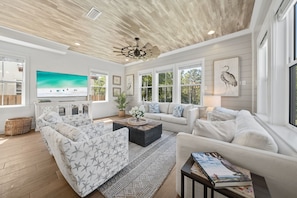 A spacious living room with a large TV, comfortable seating, and a ceiling fan. - Walk to Gulf Place~Private Pool~Dogs OK~EV Charger (Santa Rosa Beach)