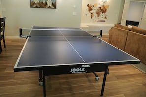 Ein Tischtennistisch auf Rollen, ein Esstisch, Stühle, eine Couch und eine Wand mit einer Karte.
