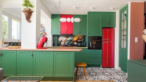 Een keuken met groene kastjes, een rode koelkast en een vloer met een patroon.