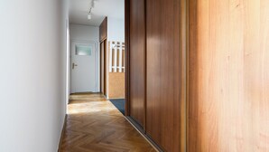 Um corredor com piso de madeira, porta branca e parede de madeira.