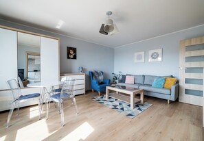 Een moderne woonkamer met een bank, stoelen, een salontafel en een spiegel.