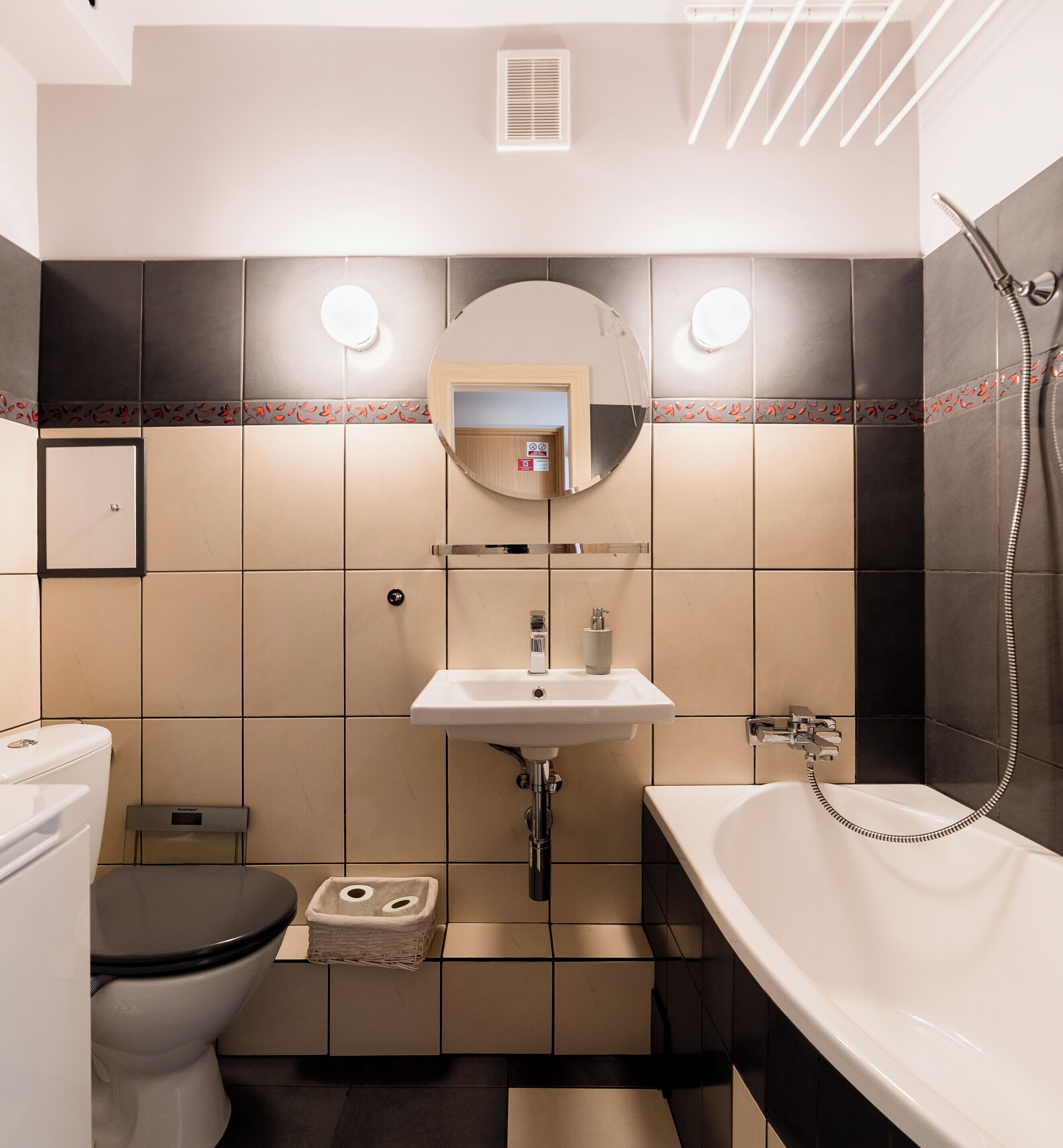 A bathroom with a toilet, sink, mirror, and bathtub.
