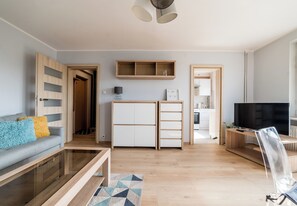 Una sala de estar moderna con sofá, mesa de centro, televisor y armarios empotrados.