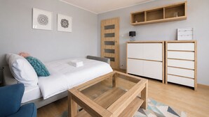 Ett modernt sovrum med en säng, ett skrivbord, en garderob och en hylla.