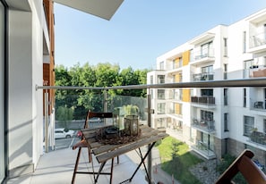 Un balcon avec une table, des chaises et une vue sur un immeuble à plusieurs étages et sur la verdure.