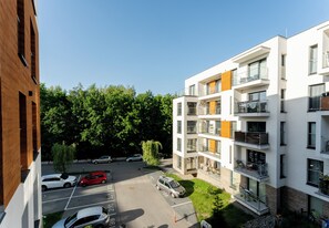 Ein mehrstöckiges Wohnhaus mit Balkonen, einem Parkplatz und umgebender Bepflanzung.