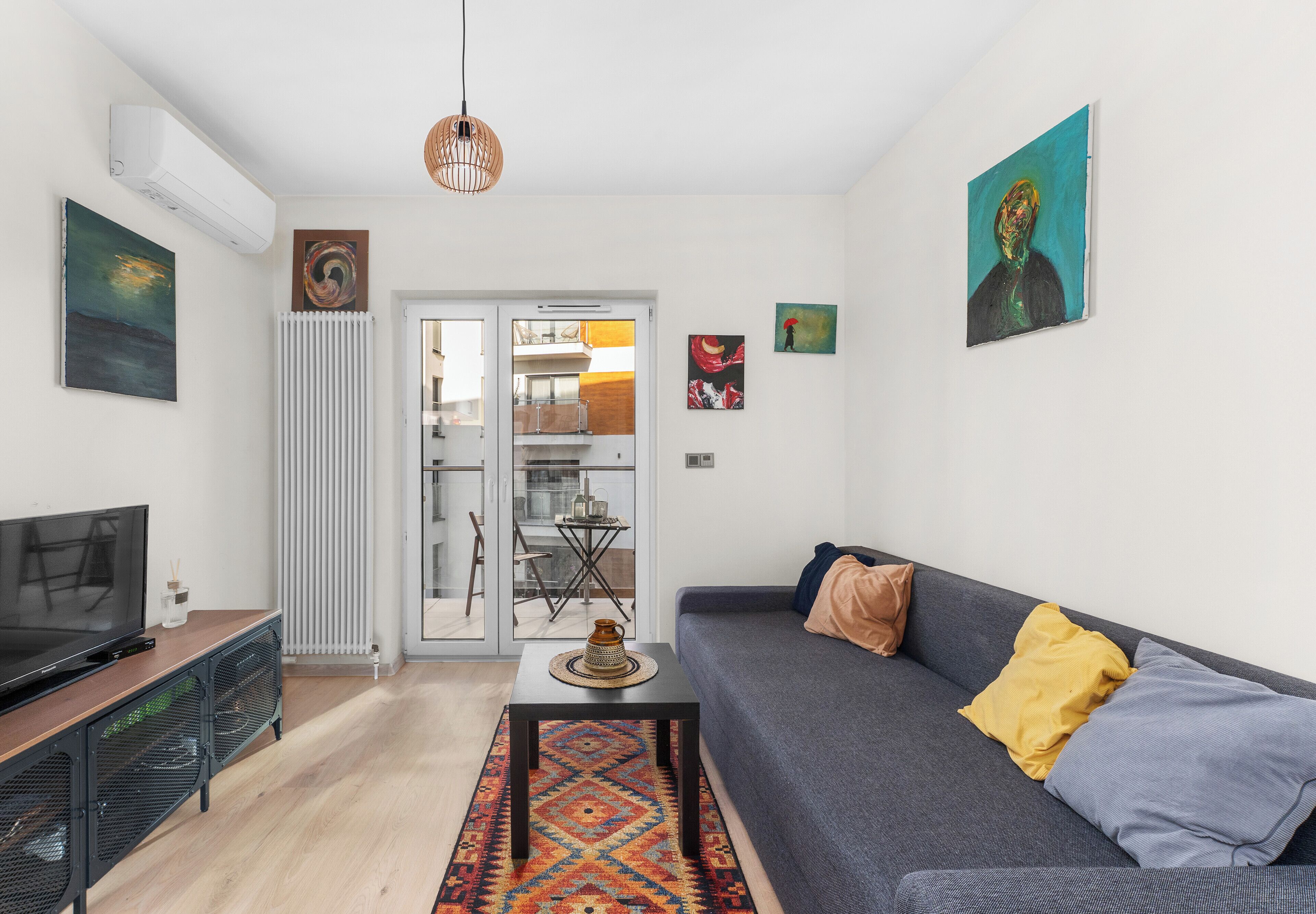 Een moderne woonkamer met een bank, een televisie en kunstwerken aan de wanden.