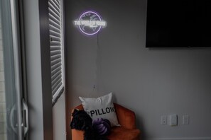Een kamer met een lamp in de vorm van een wereldbol, een kussen met de tekst 'PILLOW', een pluchen speeltje en een televisie aan de muur.