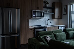 Una cucina moderna con elettrodomestici in acciaio inossidabile, un forno a microonde e un divano rivestito in verde.